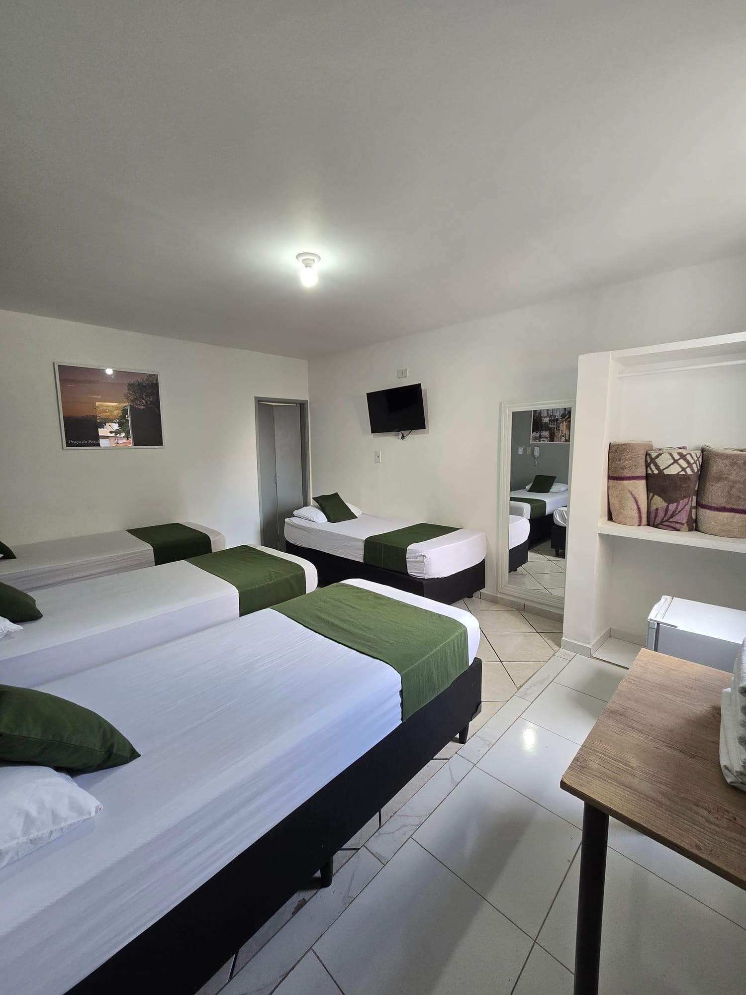 Suíte do Hotel Dona Lú com cama de casal e camas de solteiro